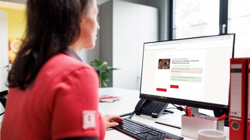 Kaufland-Verkaufsmitarbeiterin am Schreibtisch mit Tastatur und Bildschirm.